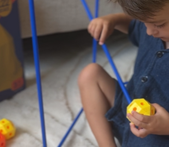 Kind dat vrolijk experimenteert met constructiespeelgoed en zo creativiteit en probleemoplossend vermogen ontwikkelt.